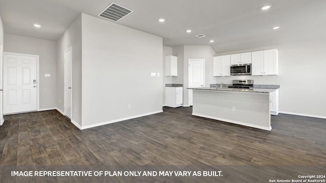 kitchen featuring appliances with stainless steel finishes, a kitchen island with sink, light stone countertops, white cabinets, and dark hardwood / wood-style flooring