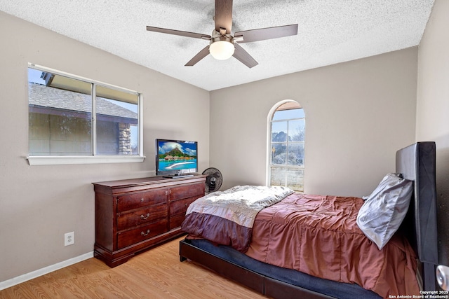 bedroom with ceiling fan, a textured ceiling, and light hardwood / wood-style flooring