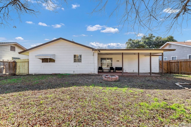 back of property with a fire pit and a patio