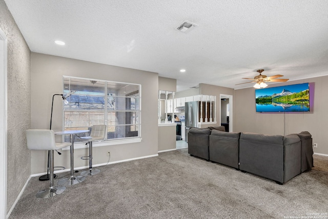 living room featuring ceiling fan, carpet floors, and a textured ceiling