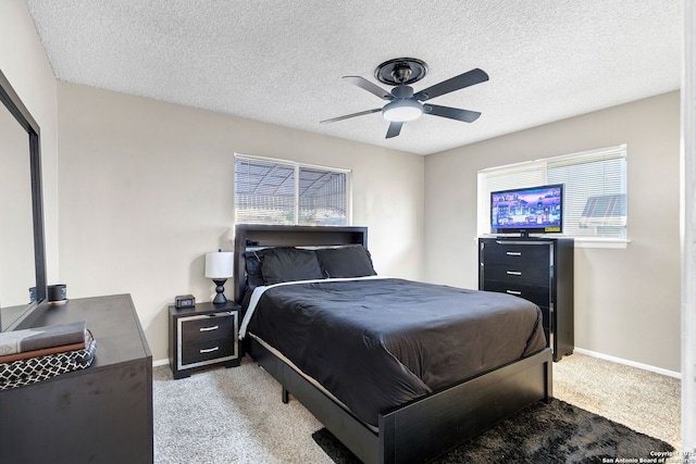 bedroom with ceiling fan, light colored carpet, and a textured ceiling