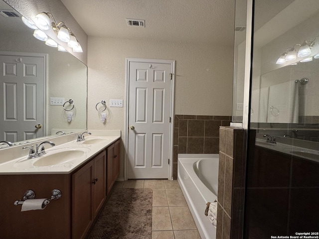 bathroom featuring vanity, tile patterned floors, a bathing tub, and a textured ceiling