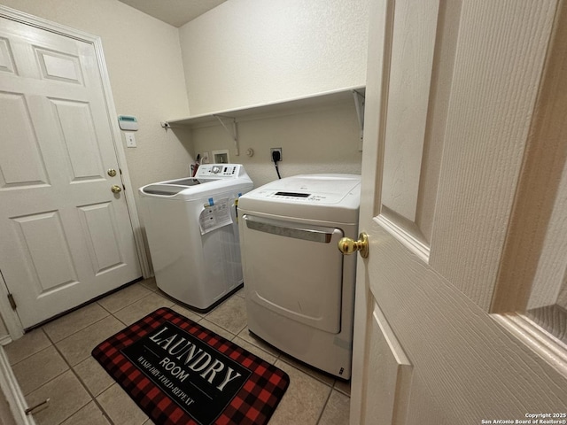 laundry area with separate washer and dryer and light tile patterned floors