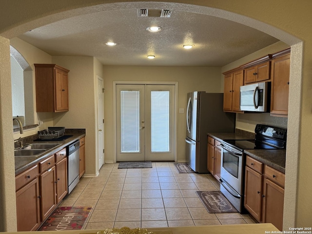 kitchen with light tile patterned flooring, appliances with stainless steel finishes, sink, a textured ceiling, and french doors