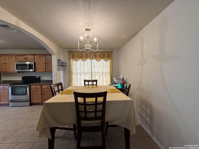 tiled dining space featuring an inviting chandelier and a textured ceiling