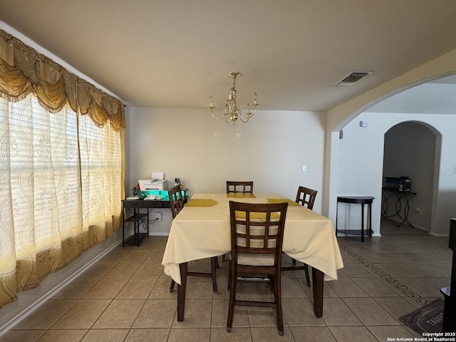 tiled dining room featuring an inviting chandelier