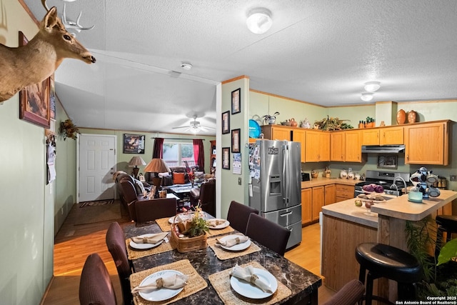 kitchen featuring stainless steel appliances, a textured ceiling, and light wood-type flooring