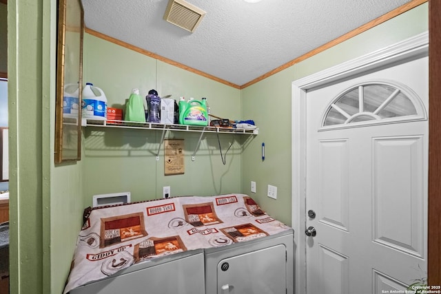 laundry room with ornamental molding, a textured ceiling, and washer and clothes dryer