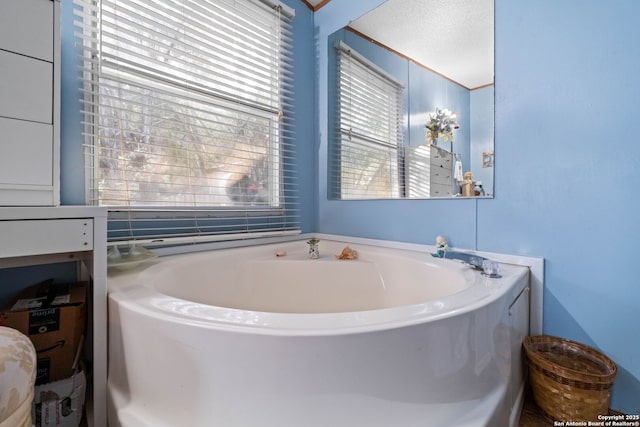 bathroom with a tub to relax in and a textured ceiling