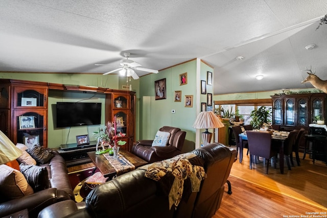 living room with ceiling fan, ornamental molding, a textured ceiling, and light wood-type flooring