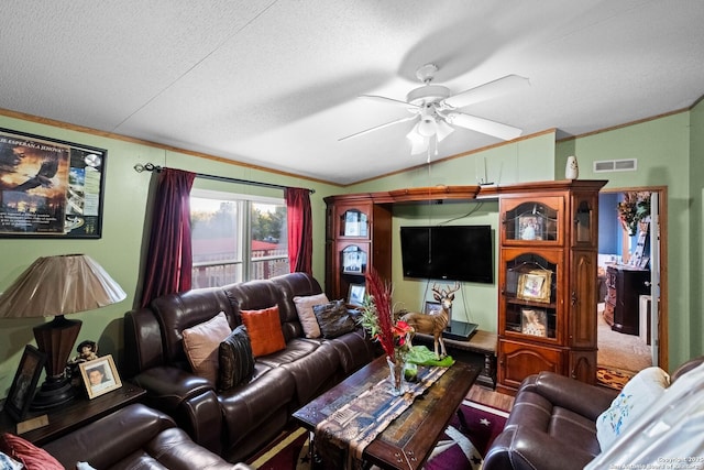 living room with ceiling fan, ornamental molding, lofted ceiling, and a textured ceiling