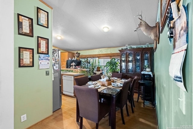 dining space featuring sink, light hardwood / wood-style floors, and a textured ceiling