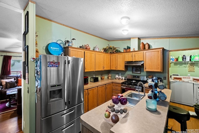 kitchen featuring dark wood-type flooring, stainless steel appliances, ornamental molding, a textured ceiling, and washing machine and clothes dryer