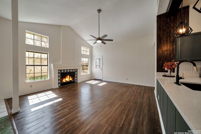 unfurnished living room with sink, dark wood-type flooring, high vaulted ceiling, and ceiling fan