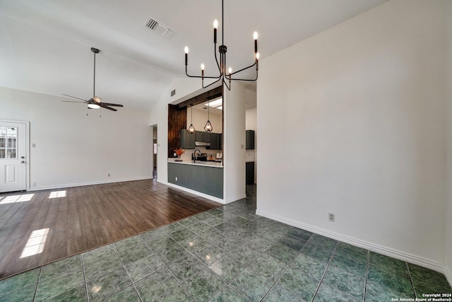 unfurnished living room featuring high vaulted ceiling, sink, ceiling fan with notable chandelier, and dark tile patterned floors