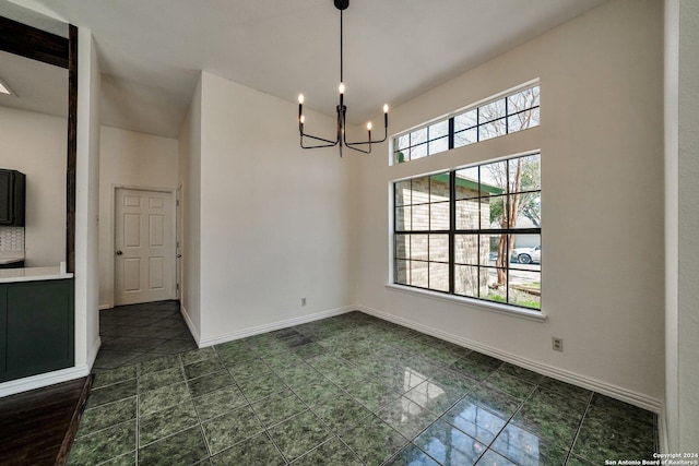 unfurnished dining area with an inviting chandelier and a towering ceiling