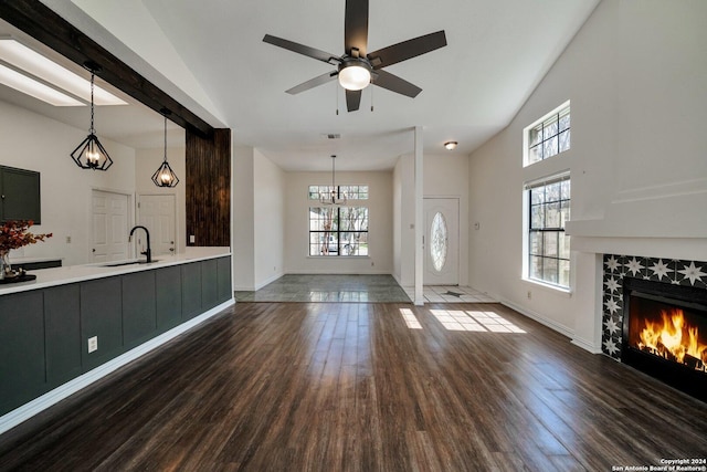 unfurnished living room featuring a tile fireplace, sink, dark wood-type flooring, and a healthy amount of sunlight