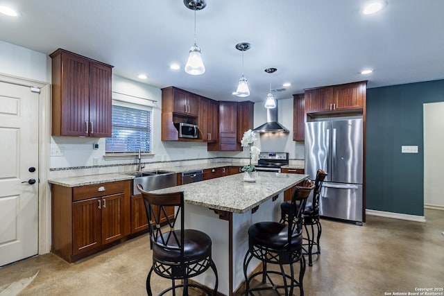 kitchen with pendant lighting, sink, stainless steel appliances, a kitchen island, and wall chimney exhaust hood