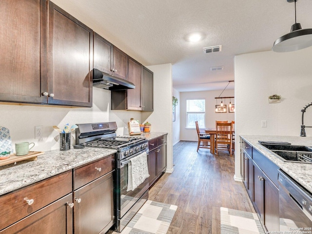 kitchen featuring sink, light stone counters, light wood-type flooring, pendant lighting, and stainless steel appliances