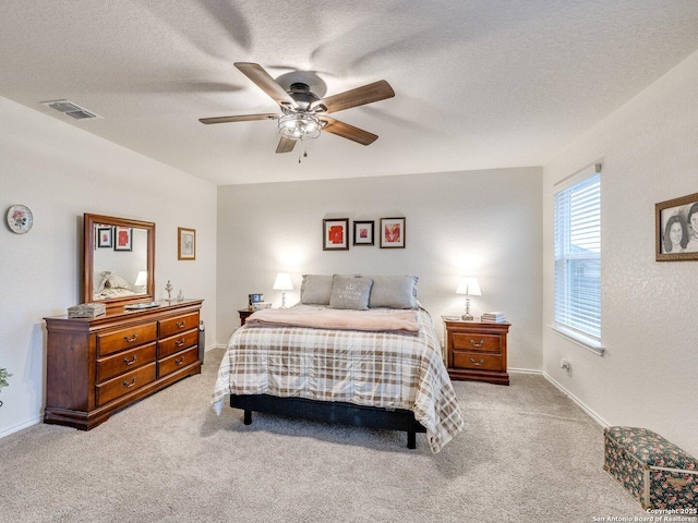 carpeted bedroom with ceiling fan and a textured ceiling