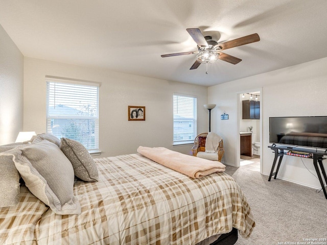 bedroom featuring ceiling fan, multiple windows, ensuite bathroom, and light carpet