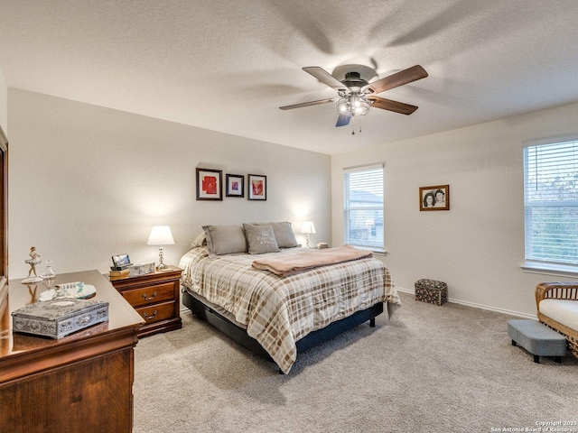 bedroom featuring ceiling fan, light colored carpet, and a textured ceiling