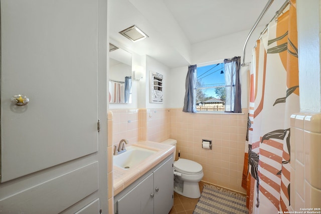 bathroom featuring walk in shower, toilet, tile walls, vanity, and tile patterned flooring