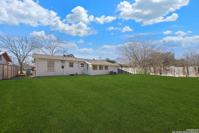 back of property with central AC unit and a lawn