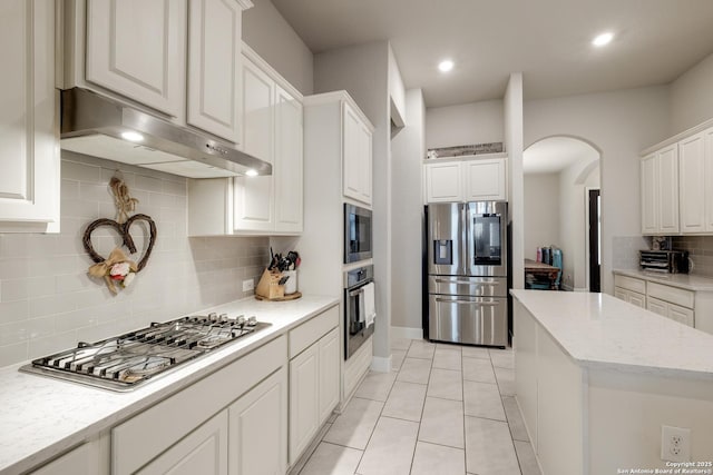 kitchen with backsplash, appliances with stainless steel finishes, light tile patterned floors, and white cabinets