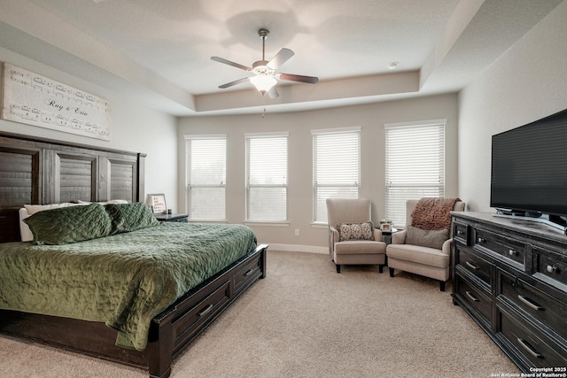 carpeted bedroom with a raised ceiling and ceiling fan