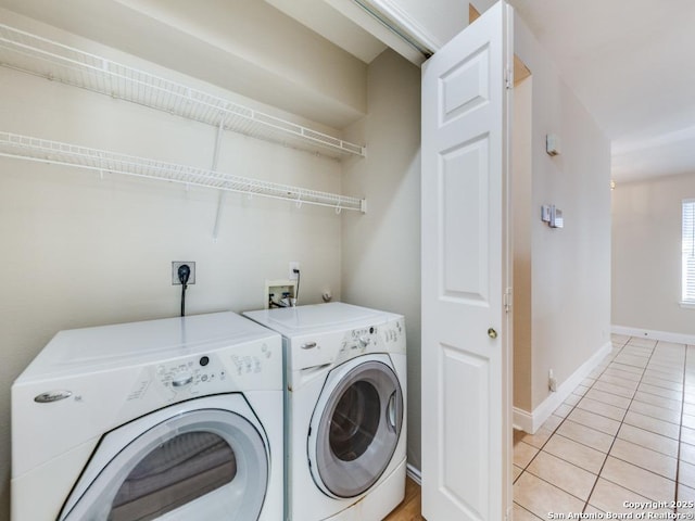 clothes washing area with washer and clothes dryer and light tile patterned flooring