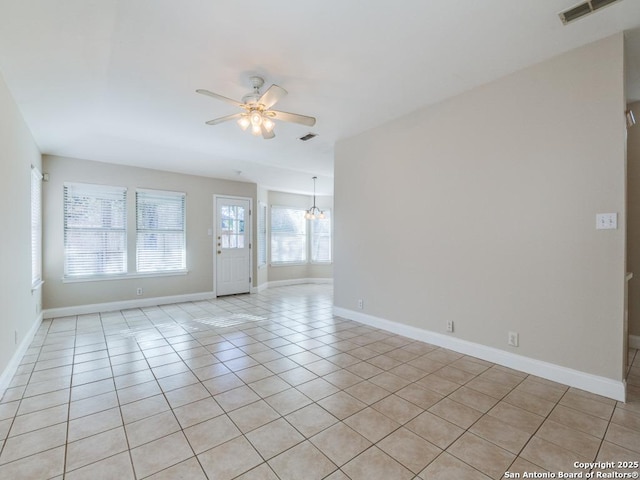 tiled spare room featuring ceiling fan with notable chandelier