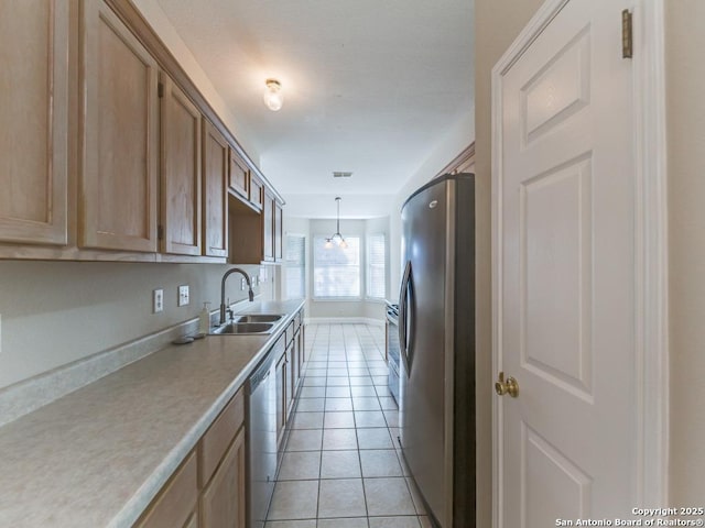 kitchen with appliances with stainless steel finishes, sink, light tile patterned floors, and decorative light fixtures