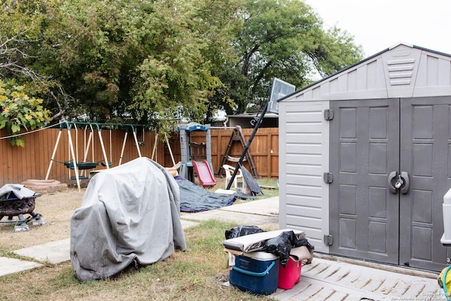 view of yard featuring a fire pit, a playground, and a storage unit