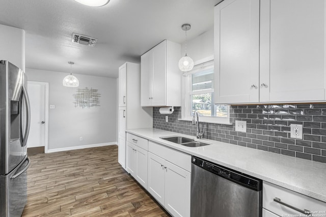 kitchen with sink, appliances with stainless steel finishes, dark hardwood / wood-style flooring, pendant lighting, and white cabinets