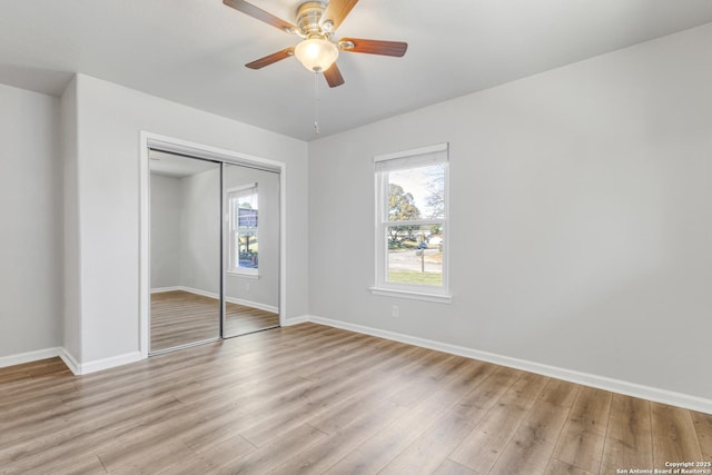 unfurnished bedroom with multiple windows, light wood-type flooring, and a closet