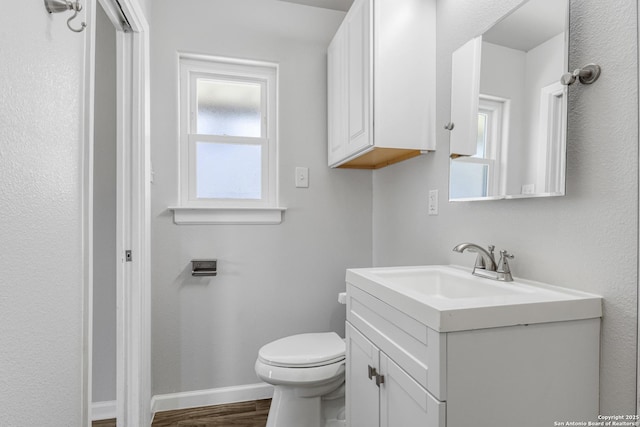 bathroom featuring hardwood / wood-style flooring, vanity, toilet, and a wealth of natural light