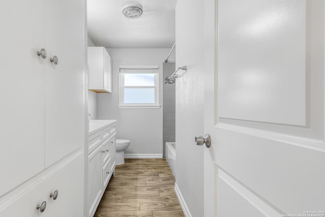 full bathroom featuring vanity, hardwood / wood-style flooring, toilet, and washtub / shower combination