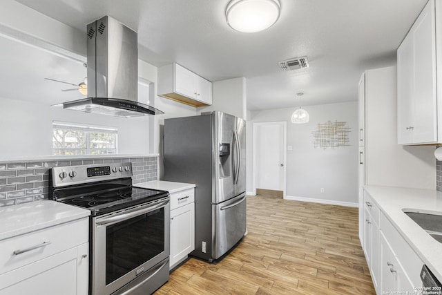 kitchen featuring appliances with stainless steel finishes, island range hood, white cabinetry, backsplash, and light hardwood / wood-style floors