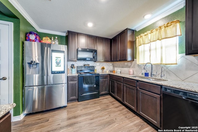 kitchen featuring sink, ornamental molding, light stone countertops, light hardwood / wood-style floors, and black appliances