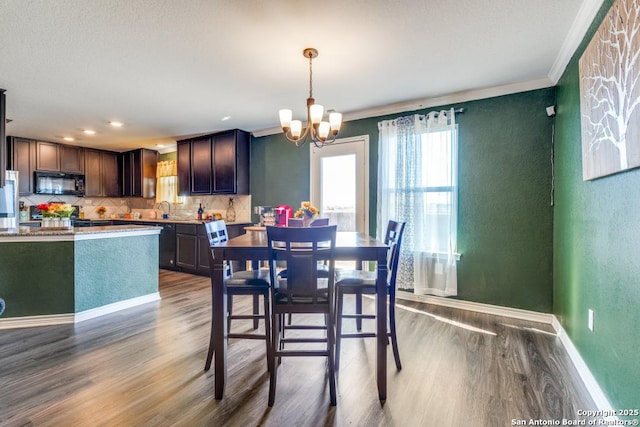 dining room featuring hardwood / wood-style floors, crown molding, a notable chandelier, and sink