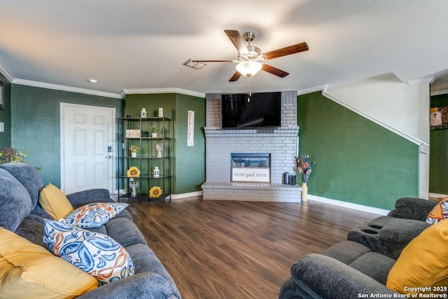 living room featuring ornamental molding, dark wood-type flooring, ceiling fan, and a fireplace