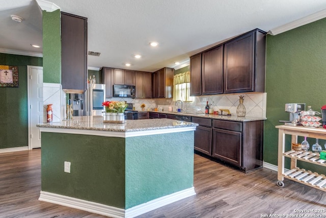 kitchen with stainless steel appliances, a center island, dark brown cabinetry, and light hardwood / wood-style flooring