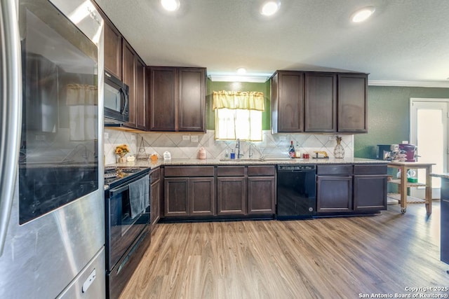 kitchen featuring sink, dark brown cabinets, black appliances, and light stone countertops