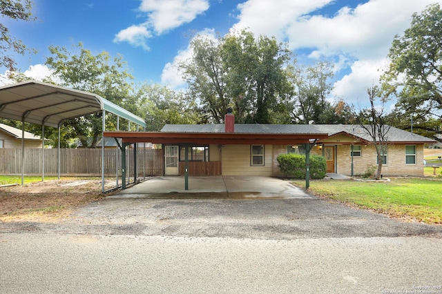 view of front of property with aphalt driveway, fence, a front yard, a carport, and a chimney