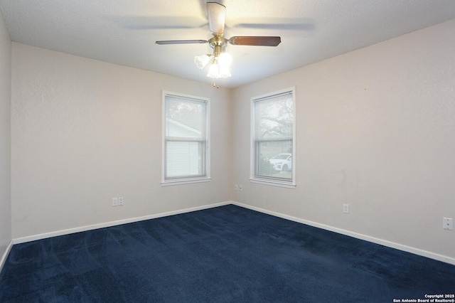 unfurnished room with ceiling fan and dark colored carpet