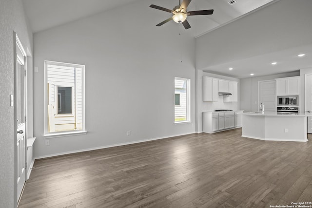 10257 Bartenheim Dr, Schertz, TX 78154 - unfurnished living room with high vaulted ceiling, ceiling fan, dark wood finished floors, a sink, and baseboards