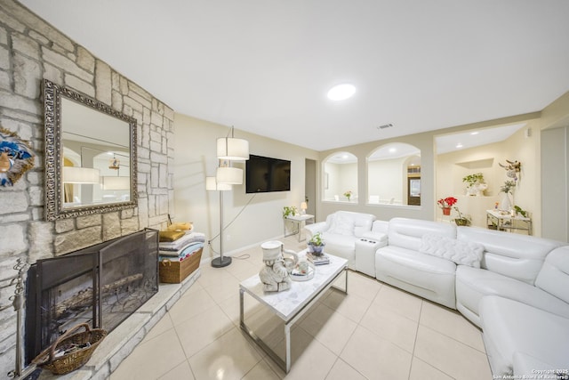 living room with a stone fireplace and light tile patterned floors