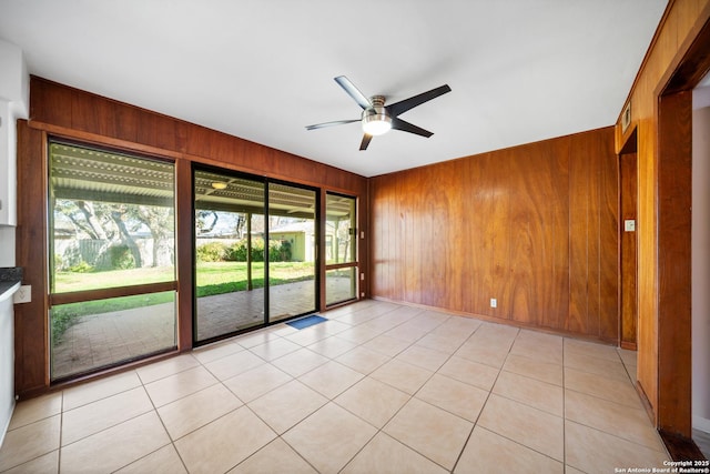 empty room with ceiling fan and wood walls