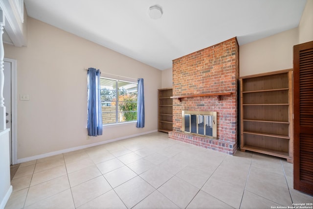 unfurnished living room featuring vaulted ceiling, a brick fireplace, and light tile patterned floors